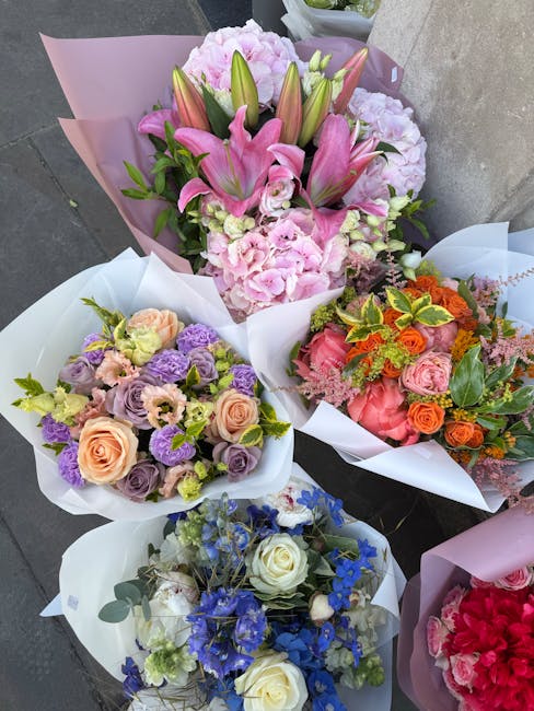Four floral bouquets arranged on a grey stone surface, featuring a variety of fresh flowers. The top bouquet highlights pink lilies, pale pink hydrangeas, and greenery, wrapped in pink and white tissu